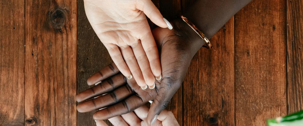 Top view of crop unrecognizable women stacking hands together on wooden surface in daytime